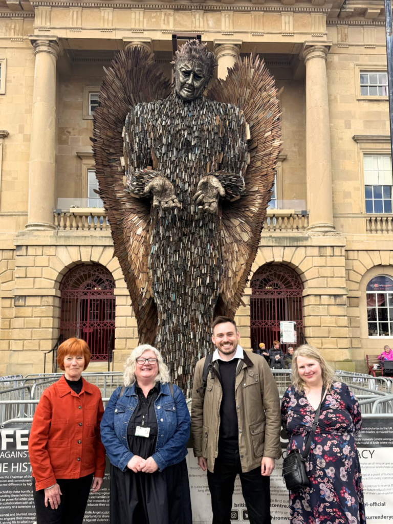 4 people stand in front of the knife angel