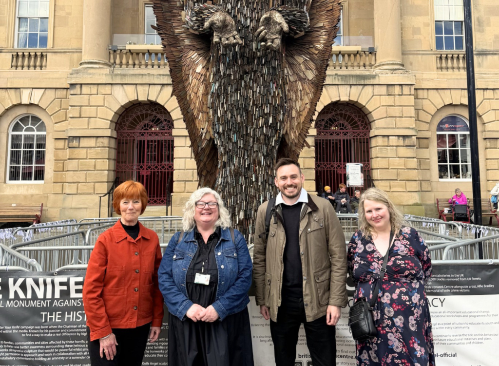 4 people stand in front of the knife angel