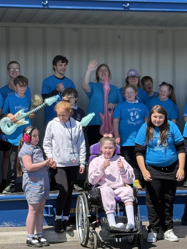 A group of people on a yard at a school signing