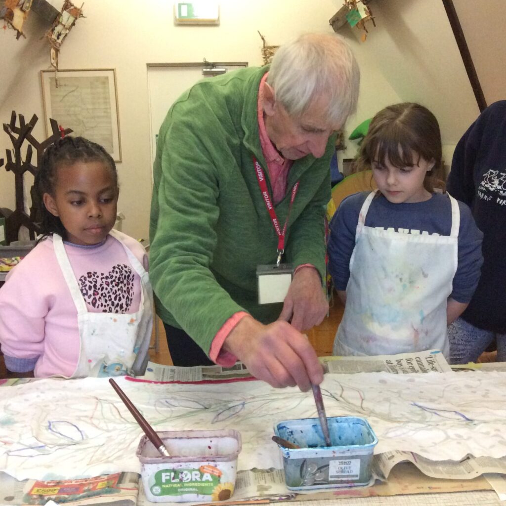 A man helps two children paint