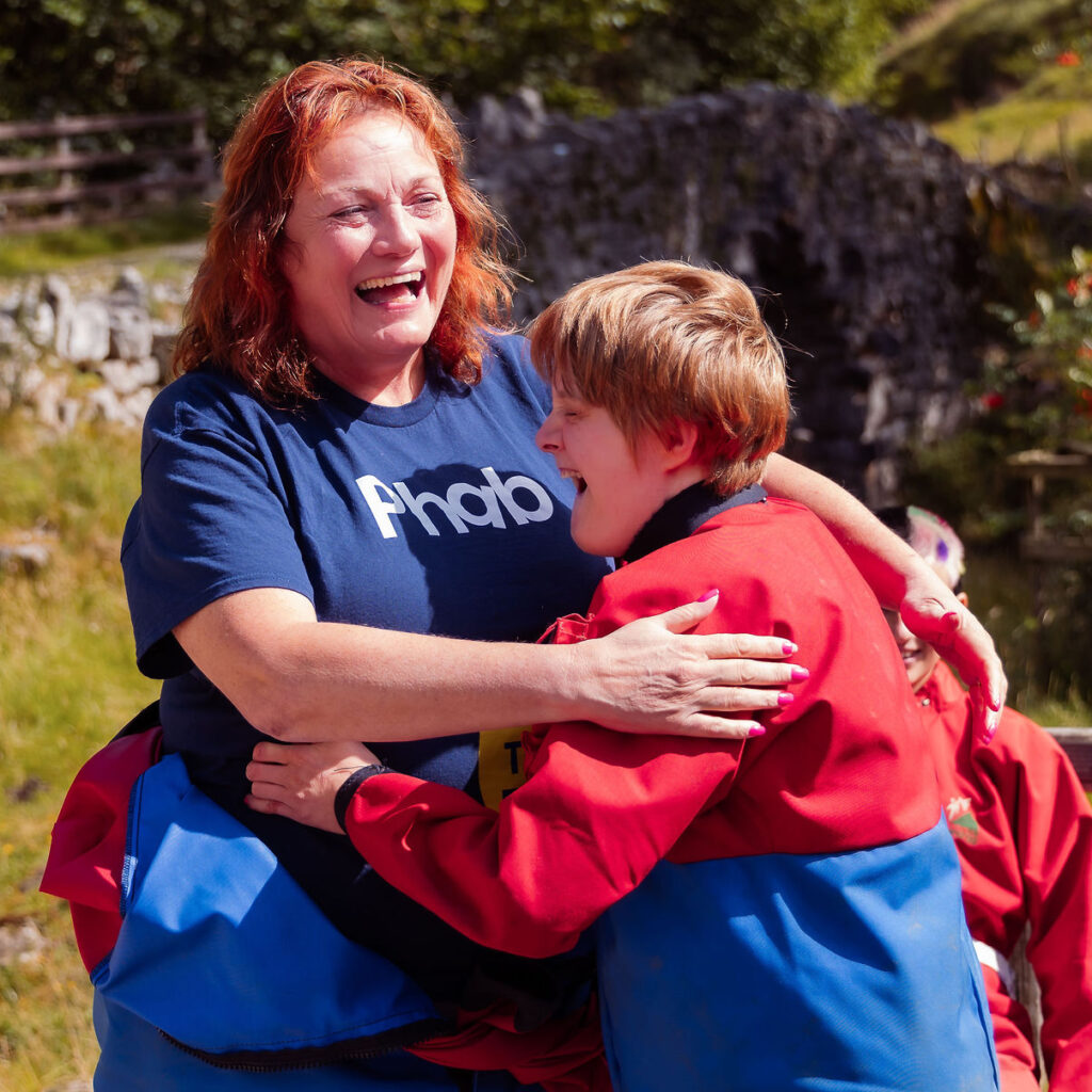 A woman and a boy in a red jacket hug. Her t-shirt reads: Phab