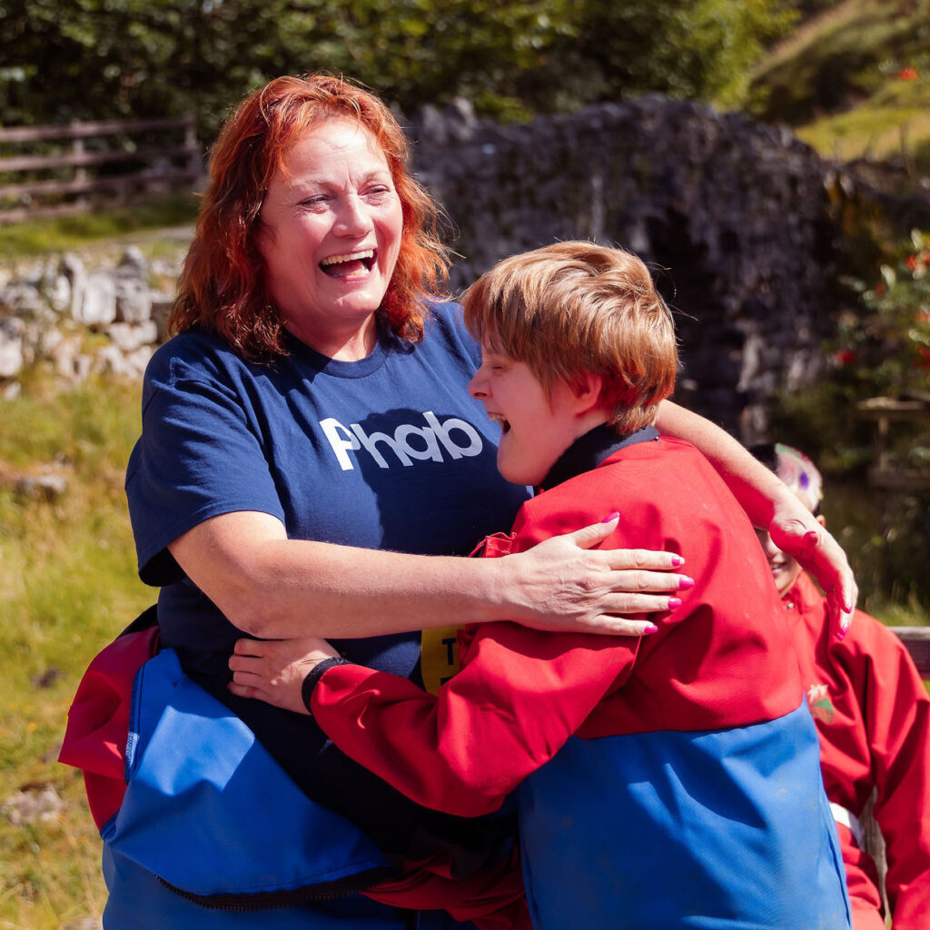 A woman and a young man in a red jacket hug