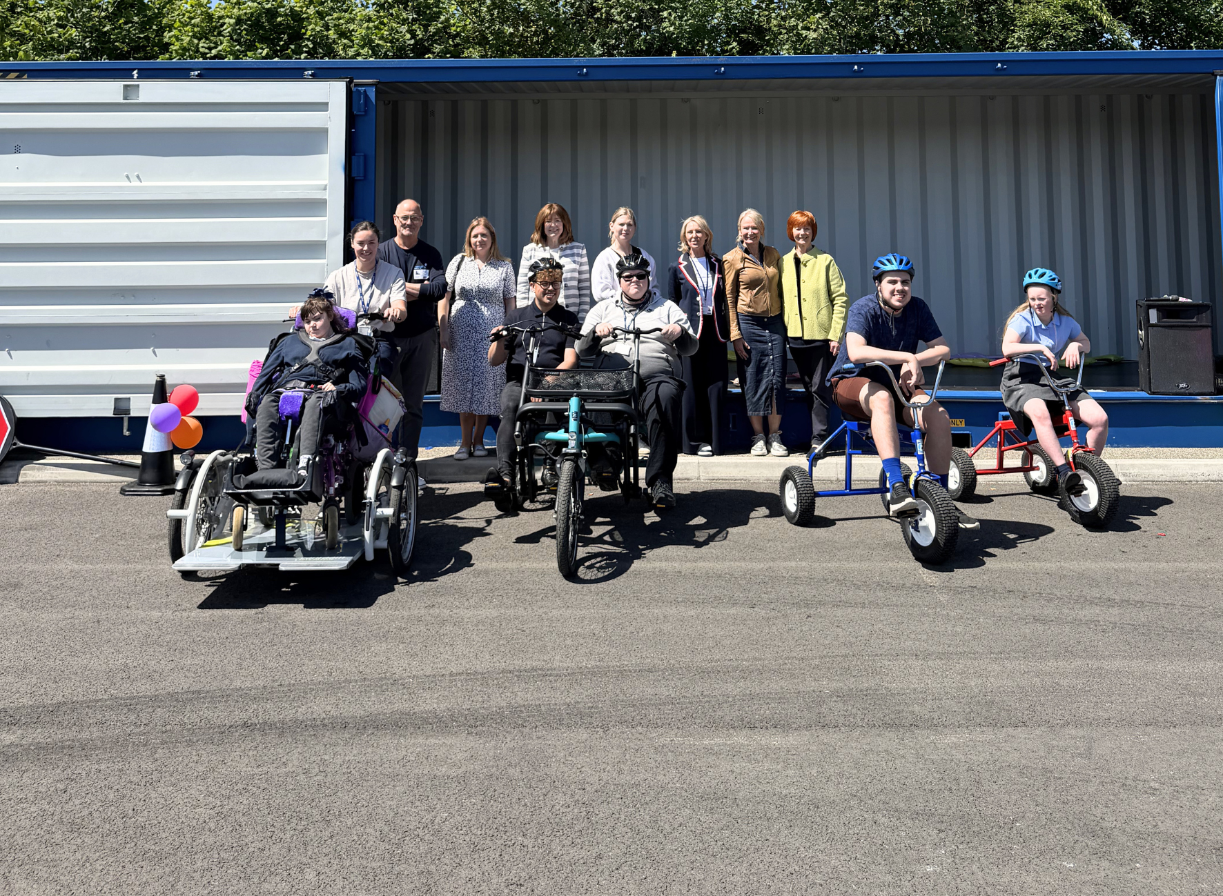 A group of people on adapted trikes in a school yard