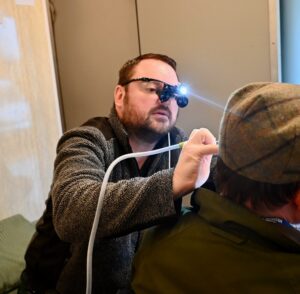 A healthcare professional performs a health check on a farmer